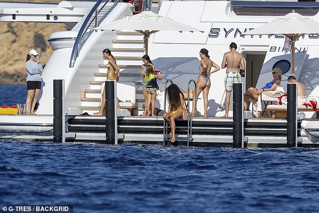 The boat was near a large cliff in the background as the celebrities spent time by the wavy blue water