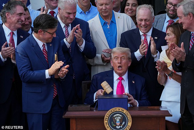 President Donald Trump (center) bangs a gavel given to him by House Speaker Mike Johnson (upper left) after signing his 'Big, Beautiful Bill' into law on Friday amid the White House's Fourth of July festivities