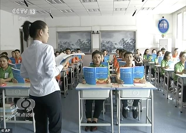 In this image from undated video footage run by China's CCTV via AP Video, young Muslims read from official Chinese language textbooks in classrooms at the Hotan Vocational Education and Training Center in Hotan