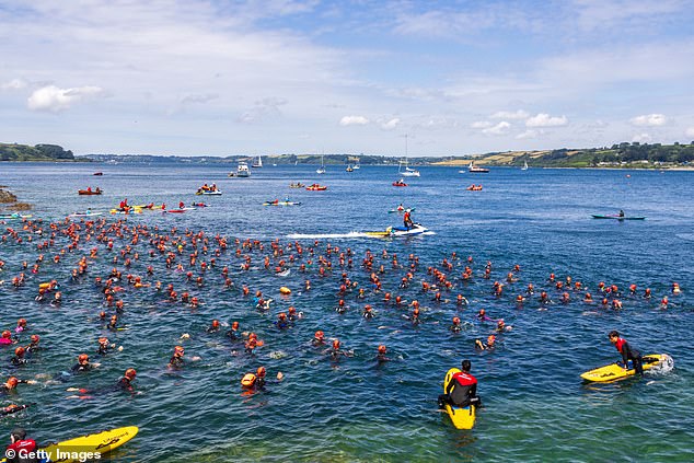 Surfers and swimmers enjoy the waves in Falmouth, Cornwall