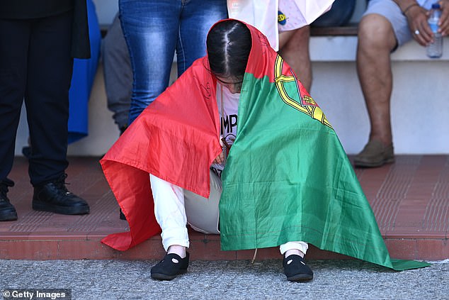 Ines is seen wrapped in the Portuguese flag as she appeared emotional during a public wake for Jota and his brother Andre on Friday