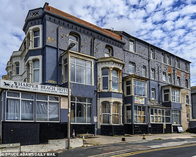 The side of the derelict Harper Beach Hotel can be seen crumbling, with paint peeling off