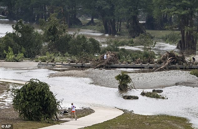 A jogger takes a detour around a flooded running path in Louise Hays Park, along the banks of the Guadalupe River