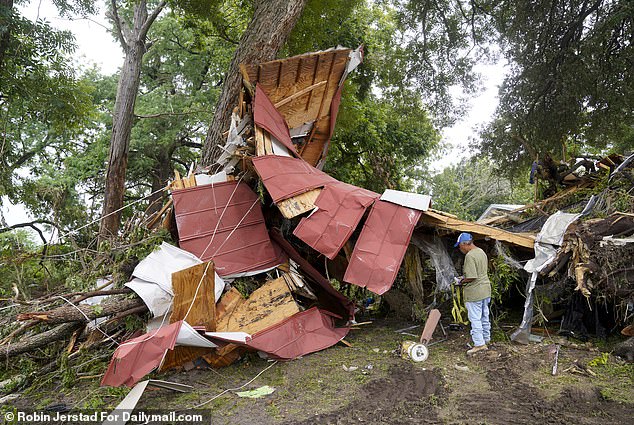 A volunteer searches for survivors in a home that was lifted off its foundation and slammed into a tree during the devastating floods of the Guadalupe Rive in Kerrville, Texas