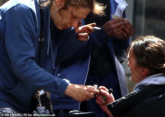 Two women pass each other a tinfoil-covered pipe as a friend rolls a cigarette in Rawson Square