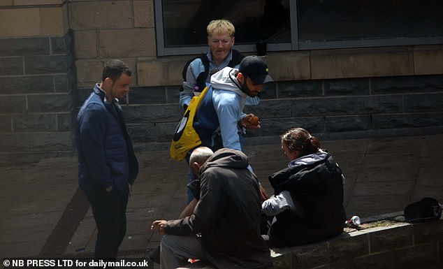 A group of people hanging out and smoking in Bradford's Crack Alley
