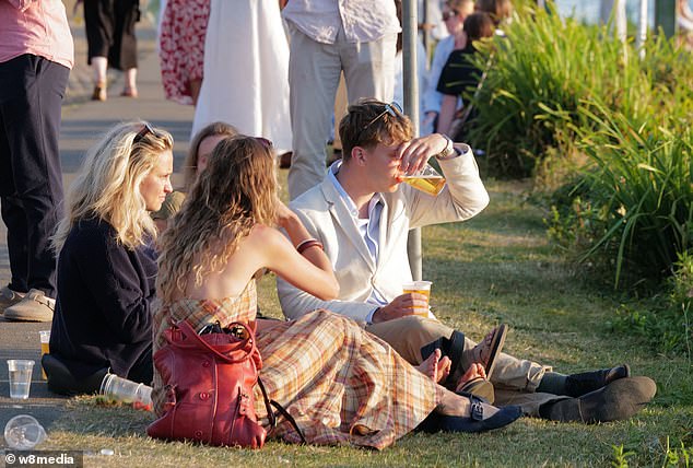 People sit on the banks of the River Thames at the Henley Regatta on Saturday sipping beer as the sun sets