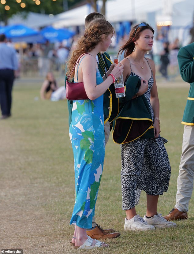 A woman in a blue and green floral dress holds on to a bottle of vodka at the Henley Regatta