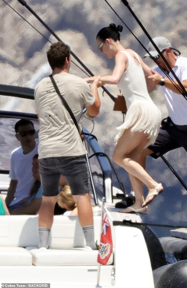 Katy wore an ivory mini dress with a fringe skirt as she was helped onto the boat