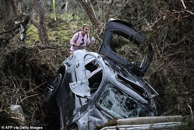 Local officials have shifted the blame to the NWS, claiming the agency cost people their lives (pictured: a volunteer searching through debris)