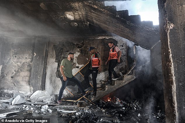 Personnel tries to extinguish a fire at the scene where a large fire broke out following Israeli army strikes on a previously warned apartment building on Omar Mukhtar Street in Gaza City