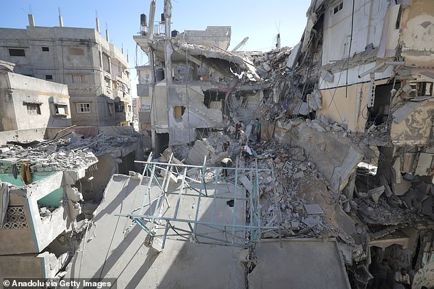 Civil defense members and Palestinian residents inspect the site and conduct search and rescue operation amid rubble of buildings after Israeli army carried out an attack on a building in the Nuseirat Refugee Camp in Gaza City