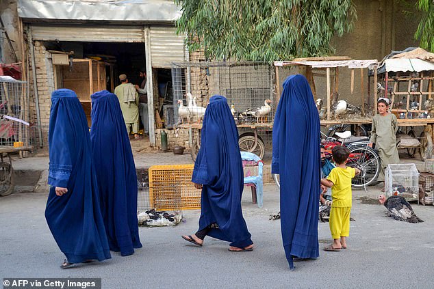 Women have been banned from speaking loudly in their own homes, and are not allowed to be heard outside (Afghan burqa-clad women walk along a street in Kandahar)