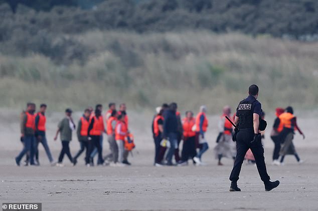 French police try to stop a group of migrants as they walk on the beach in an attempt to get on an inflatable dinghy to cross the English Channel to reach Britain, from the beach of Petit-Fort-Philippe in Gravelines, near Calais, France, July 2, 2025