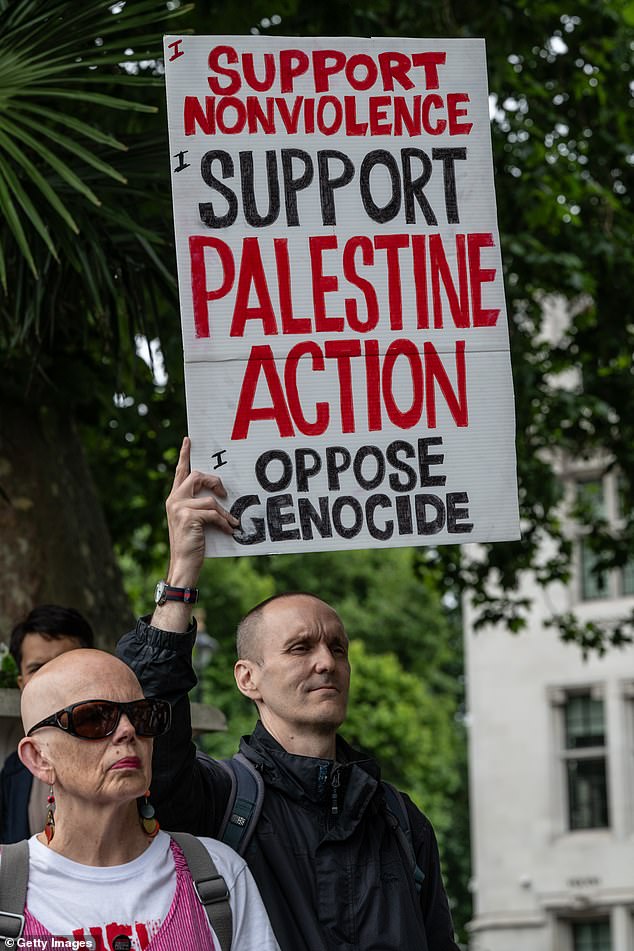 Activists sit with placards at the Gandhi statue on July 5, 2025 in London, England. Following Friday's failed legal challenge, the Home Secretary's order to proscribe Palestine Action as a terrorist group has become law
