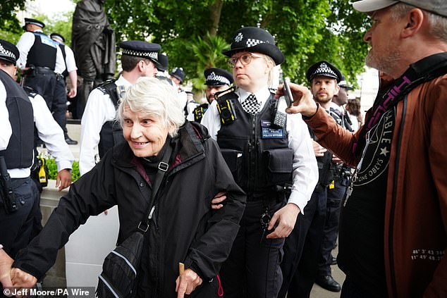 Metropolitan Police officers remove 83-year-old Reverend Sue Parfitt from a protest in support of Palestine Action, organised by the Defend Our Juries group, in front of the Mahatma Gandhii statue in Parliament Square, central London