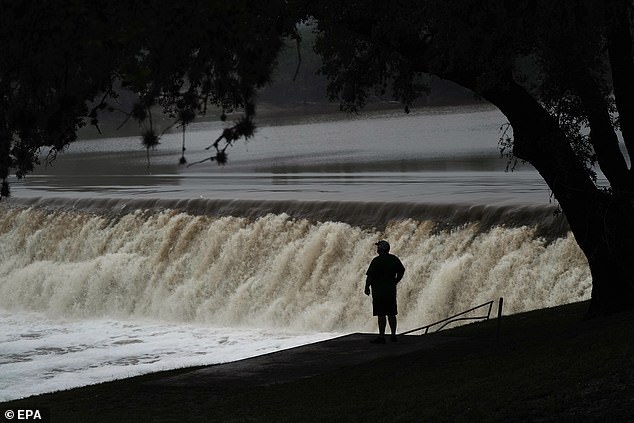 People watch the Guadalupe River flow over a dam