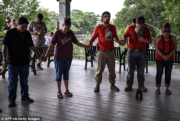 The death toll has risen to at least 80 people, 28 of whom are children (Pictured: people gather for a prayer circle near the Guadalupe River)