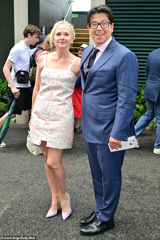 Comedian Michael, 49, cut a dapper figure in a navy suit which he layered over a crisp white shirt and dark tie for the outing