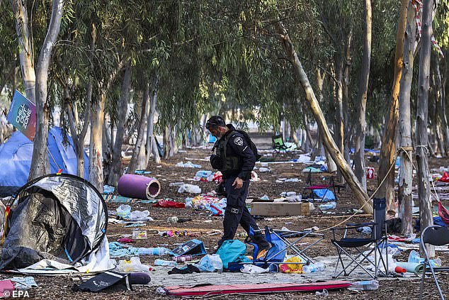 An Israeli officer walks on the ground of the Nova Festival in Re'im, Israel, 17 October 2023