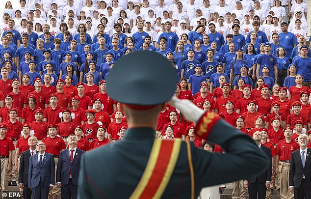 A Russian serviceman stands in front of activists of Russian Patriotic movements dressed in colors of the National flag attending a flag raising ceremony during the Russia Day celebrations at the Victory museum in Moscow, Russia, 12 June 2025
