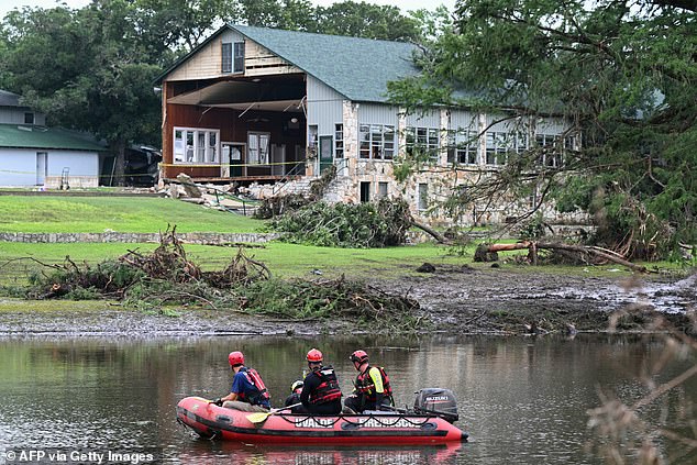 A search and rescue team looks for people along the Guadalupe River near a damaged building at Camp Mystic in Hunt, Texas