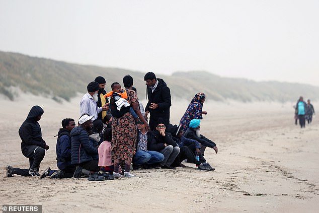 A group of migrants get on an inflatable dinghy in an attempt to cross the English Channel to reach Britain, from the beach of Petit-Fort-Philippe in Gravelines, near Calais