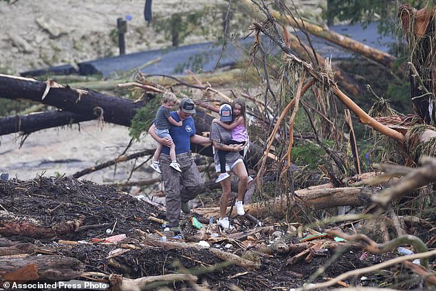 People climb over debris on a bridge atop the Guadalupe River after a flash flood swept through the area