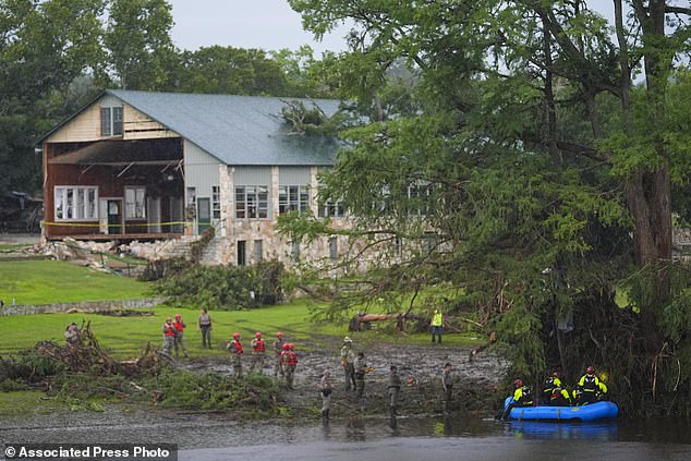 Rescue workers are seen on land and on a boat as they search for missing people near Camp Mystic along the Guadalupe River