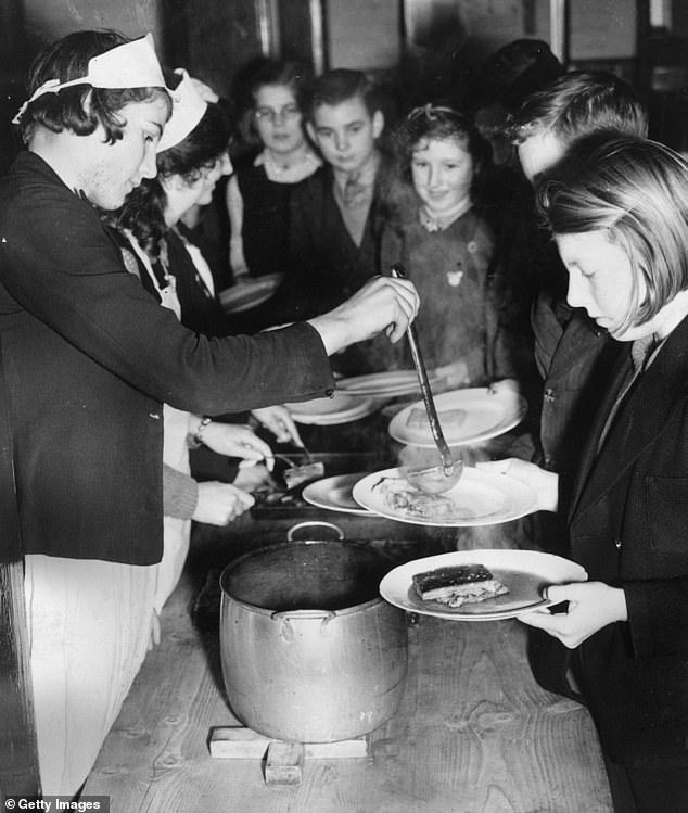February 1942: Children queuing for lunch at the Holbrook School canteen in East Suffolk. As part of ther war effort the children grow their own vegetables and breed their own rabbits for meat under the auspices of the National Federation of Young Farmers