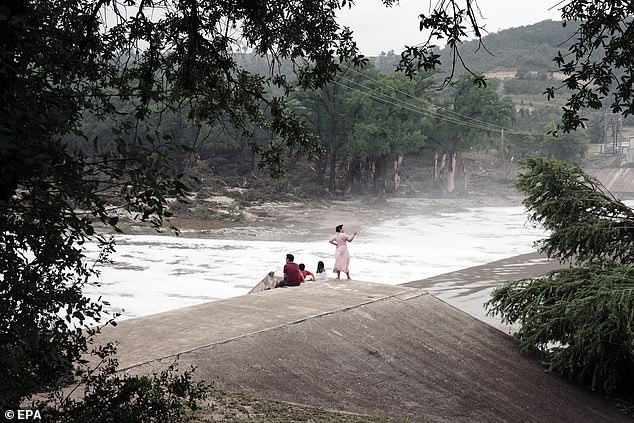 People watch the Guadalupe River flow over a dam in Kerrville. President Donald Trump rejected the idea of investigating whether NWS cuts had left key vacancies, saying that NWS cuts had anything to do with the tragedy were 'disgusting'