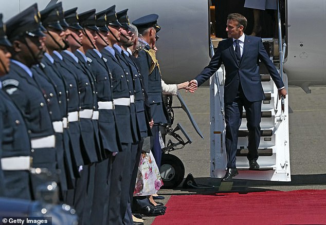 France's President Emmanuel Macron shakes hands with delegates as he leaves the plane at RAF Northolt in Windsor, England
