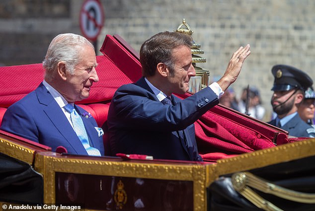 The King looks on as President Macron waves to the crowd at the royal welcoming procession in Windsor