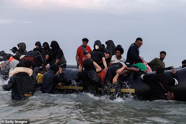 A woman is helped onto a small boat with her child in the thick fog on July 02, 2025 in Gravelines, France