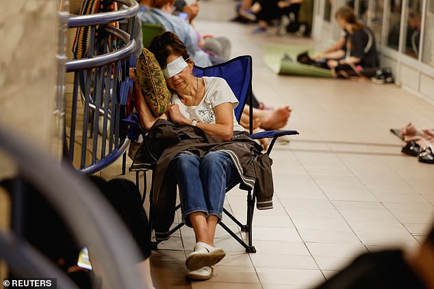 A woman covers her eyes to sleep as she takes shelter inside a metro station during an air raid alert amid Russia's attack on Ukraine, in Kyiv, Ukraine, July 8, 2025