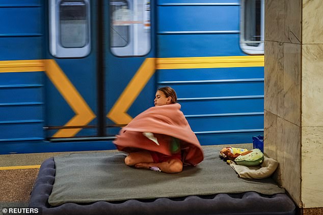 A girl covers herself with blanket as she takes shelter inside a metro station during an air raid alert amid Russia's attack on Ukraine, in Kyiv, Ukraine, July 8, 2025