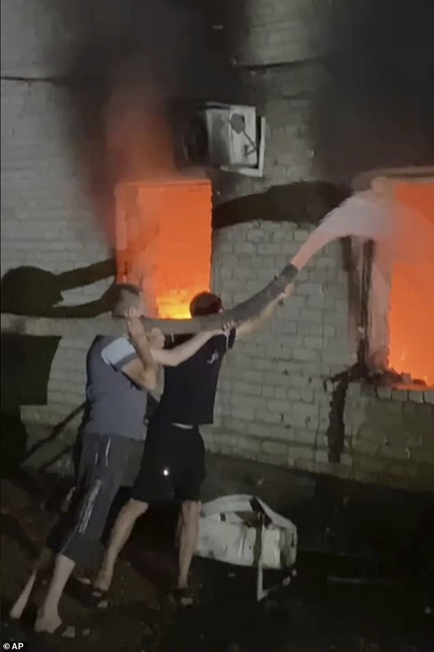 Volunteers try to put out a fire after a Ukrainian drone attack on the Rylsk Central District Hospital and its ambulance building in Rylsk in the western Kursk region of Russia