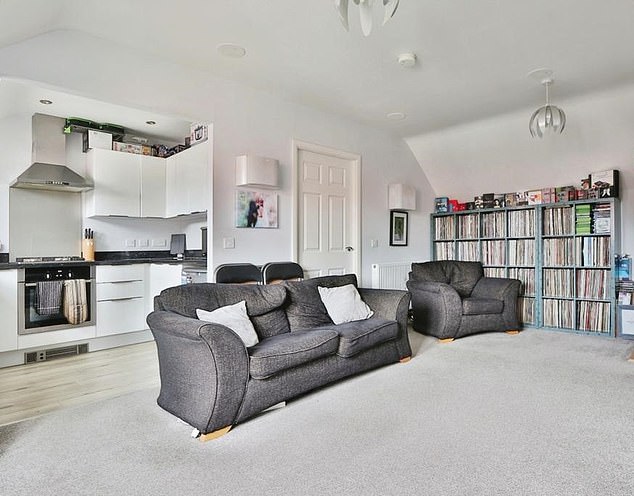 The home the influencer rents includes an open-plan kitchen living room with grey furniture and white walls