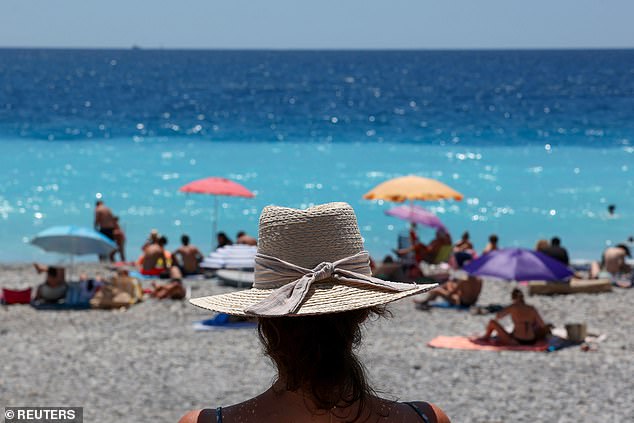 A woman watches activities on the beach on a warm and sunny summer day on the Promenade des Anglais in Nice, France, July 9