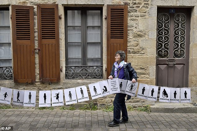 A woman holds a banner representing anonymous victims during a demonstration ahead of the verdict in the trial of Joel Le Scouarnec
