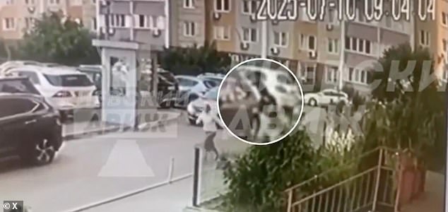 The assailant is seen firing a final lethal shot at the colonel lying on the ground as a woman runs away