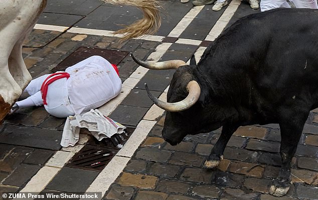 A tourist is toppled by a bull at this year's event, with reports of injuries already in double figures with four days left to run