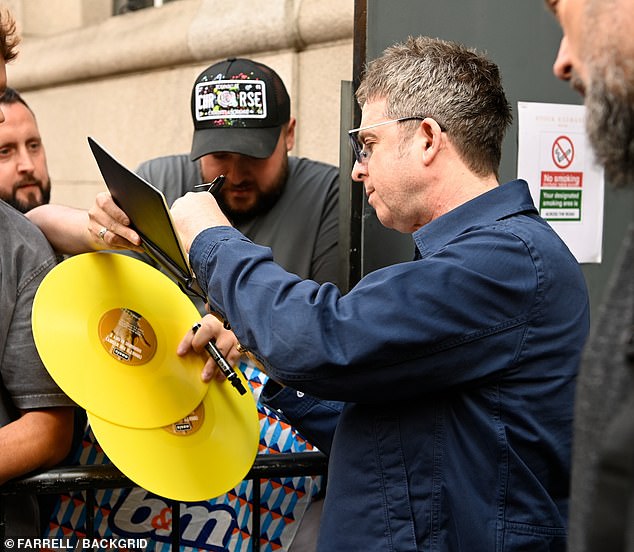 Despite his frosty exterior, Noel - who was pictured biting on an apple - did make time for supporters by signing vinyl tapes and CDs after he stepped out of a blacked out motor