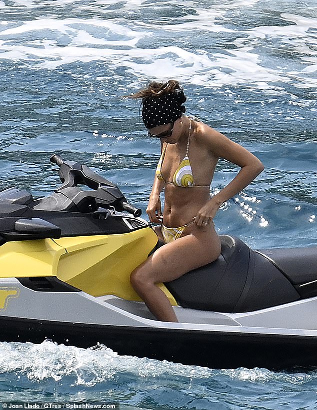 She looked to be adjusting her bikini bottoms as she sat on board the jet ski