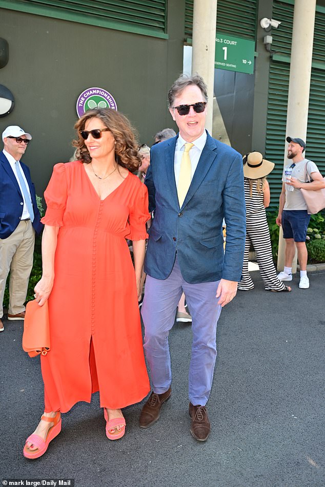 His wife put on a summery display in a button up coral orange summer dress and matching pink sandals