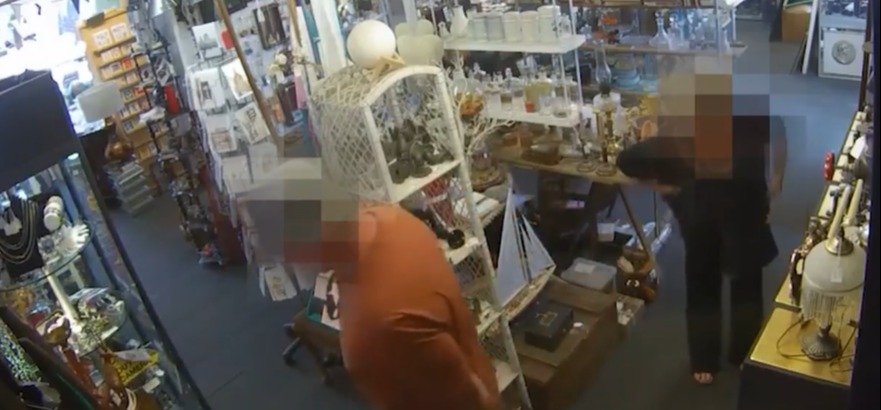 Security camera footage of a shop interior showing two people browsing.