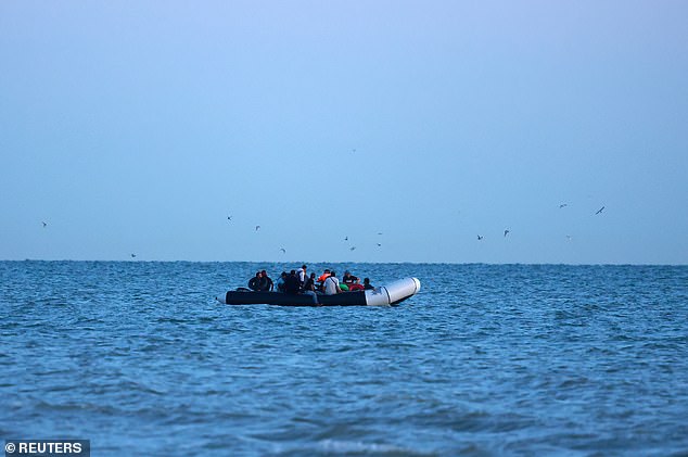 Pictured: A group of migrants sit on a dinghy trying to cross the English Channel today