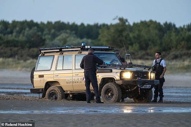 French police are pictured on the beach in Gravelines today where migrant boats are attempting to cross the Channel