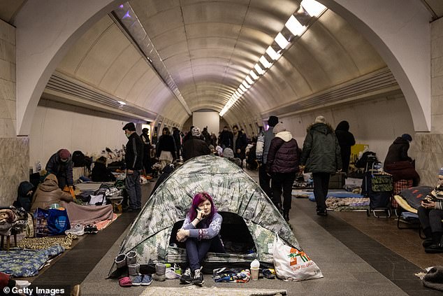Pictured are Ukrainians hiding in a make-shift bomb shelter during a Russian missile attack on the capital of Kyiv