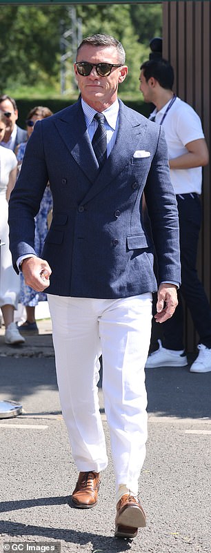 Luke Evans cut a dapper figure in a navy fitted suit jacket and blue and white striped shirt